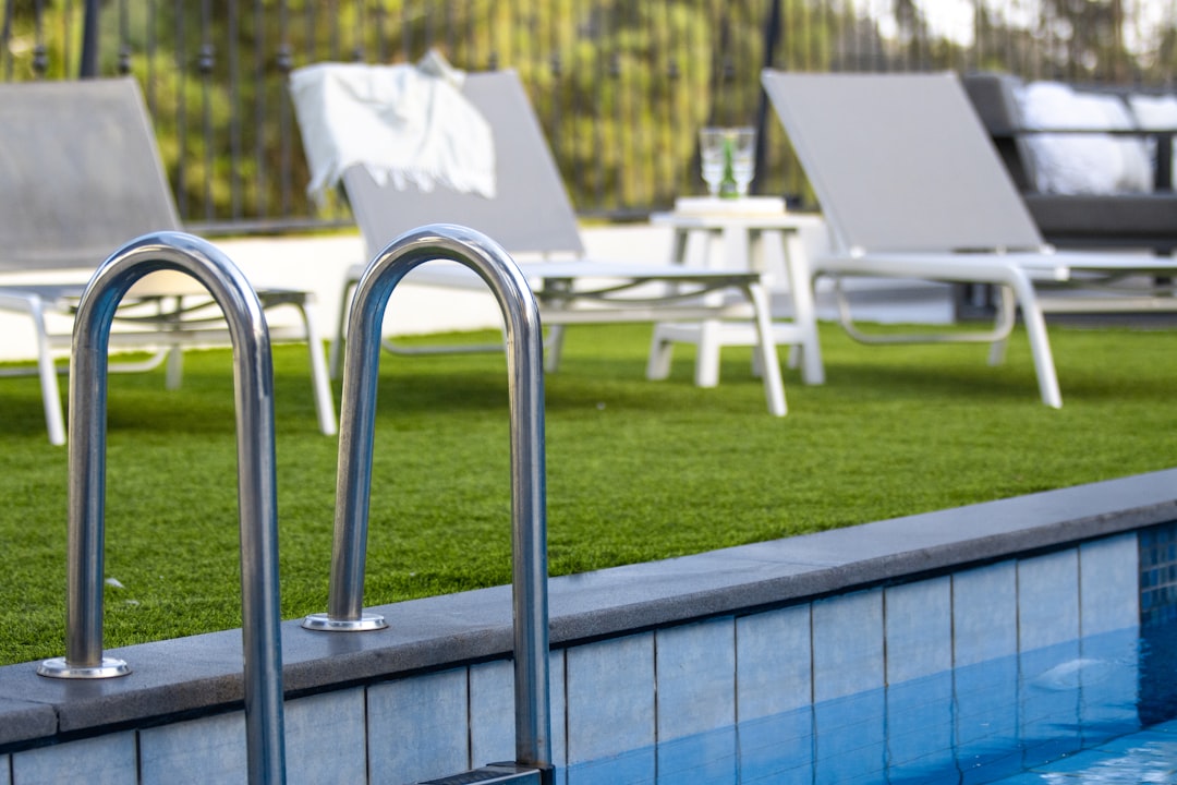 Swimming pool ladder with lounge chairs on grass