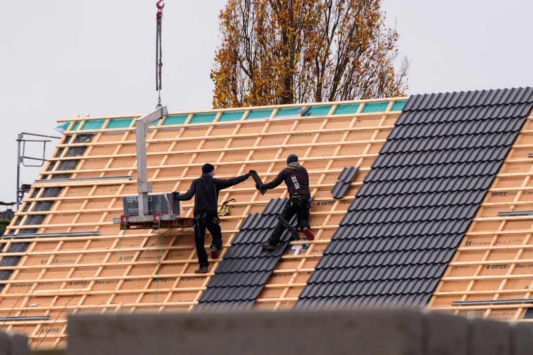 Workers installing roof tiles on a new building
