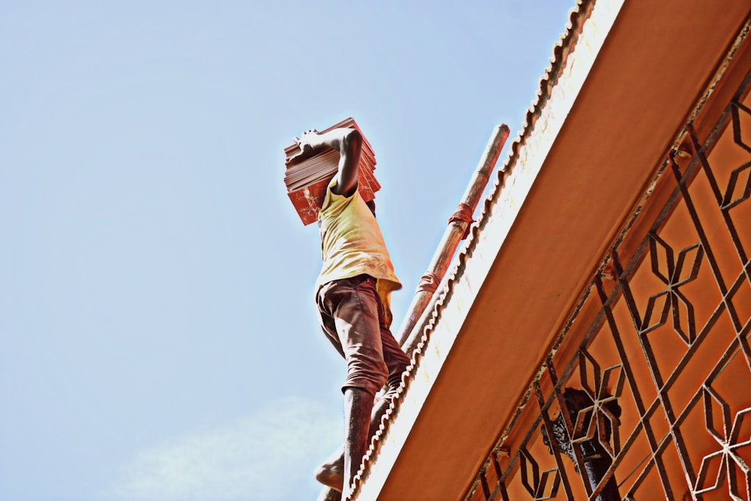 man in gray shirt and brown pants jumping on orange metal railings during daytime